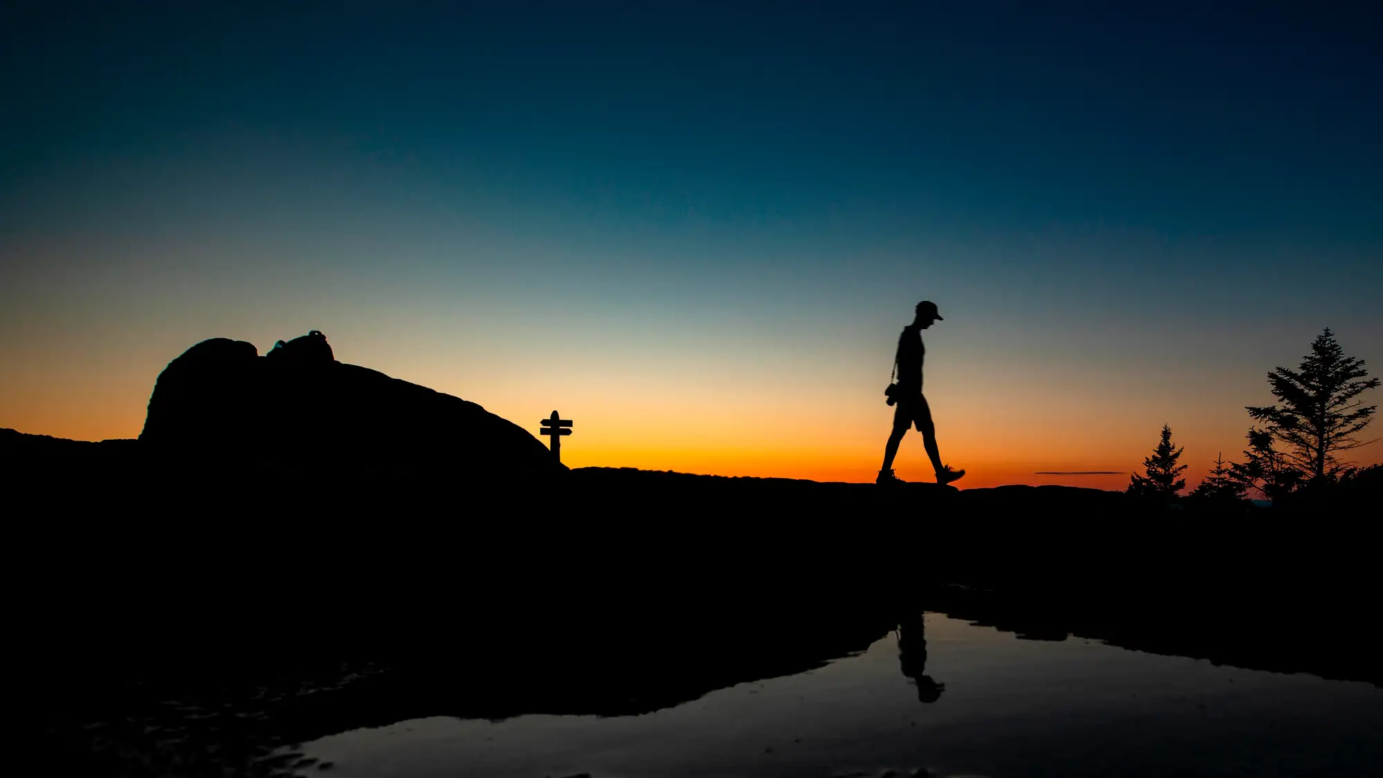 Silhouette of a hiker walking along a ridgeline at sunset