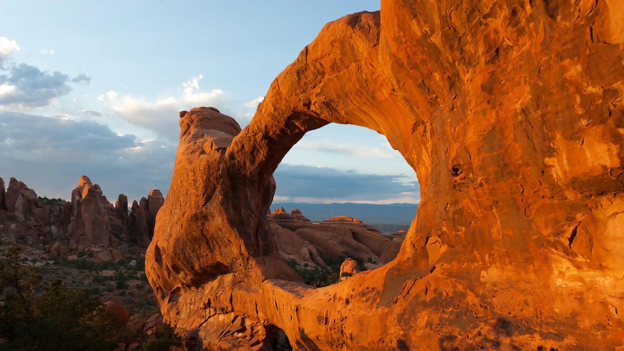 a broad, red arch with rock pinnacles in the background